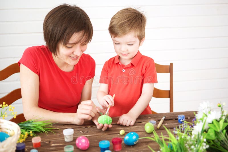 Fostra och hennes son som målar färgrika easter ägg Lyckliga easter för familjmamma- och barnsonmålarfärg ägg med färger Förbered arkivbilder Fostra och hennes son som målar färgrika easter ägg Lyckliga easter för familjmamma- och barnsonmålarfärg ägg med färger Förbered arkivbilder