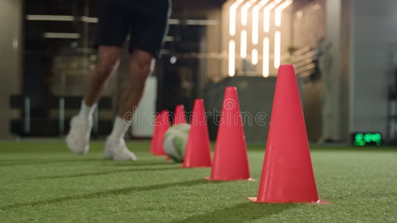 Fotbollsspelare som spelar fotbollsspel på golvet i gym, oigenkännlig man som springer med arkivfilmer