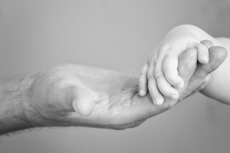 Foto alta vicina della mano del bambino della tenuta del padre in bianco e nero immagini stock libere da diritti