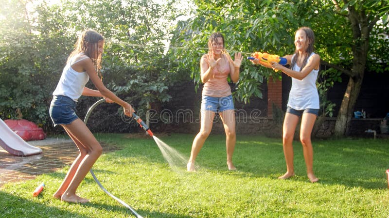 Photo Of Happy Children Having Water Gun Fight At House Backyard Garden