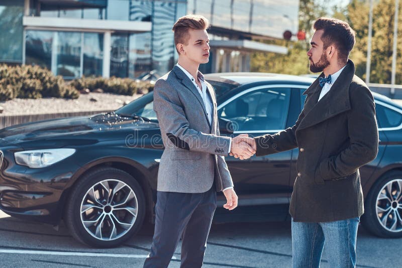 Foto av tv? smarta eleganta m?n, som har ett avtal om bilen arkivbilder Foto av tv? smarta eleganta m?n, som har ett avtal om bilen arkivbilder