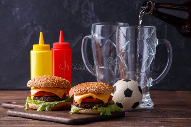 Foto av två hamburgare, exponeringsglas, fotbollboll, ketchup fotografering för bildbyråer Foto av två hamburgare, exponeringsglas, fotbollboll, ketchup fotografering för bildbyråer