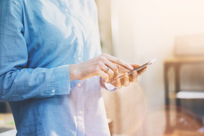 Foto bedrijfsvrouw die jeansoverhemd, wat betreft het smartphonescherm dragen Modern zolderbureau Vage achtergrond horizontaal royalty-vrije stock fotografie Foto bedrijfsvrouw die jeansoverhemd, wat betreft het smartphonescherm dragen Modern zolderbureau Vage achtergrond horizontaal royalty-vrije stock fotografie