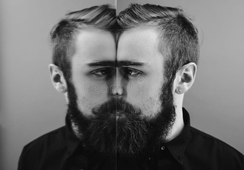 Foto in bianco e nero di un uomo con una barba e una pettinatura alla moda vestite nella condizione nera della camicia accanto al fotografie stock Foto in bianco e nero di un uomo con una barba e una pettinatura alla moda vestite nella condizione nera della camicia accanto al fotografie stock