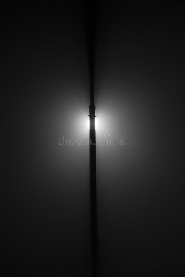 Foto in bianco e nero minimalistic astratta di una lampada di via su una notte nebbiosa immagine stock libera da diritti Foto in bianco e nero minimalistic astratta di una lampada di via su una notte nebbiosa immagine stock libera da diritti