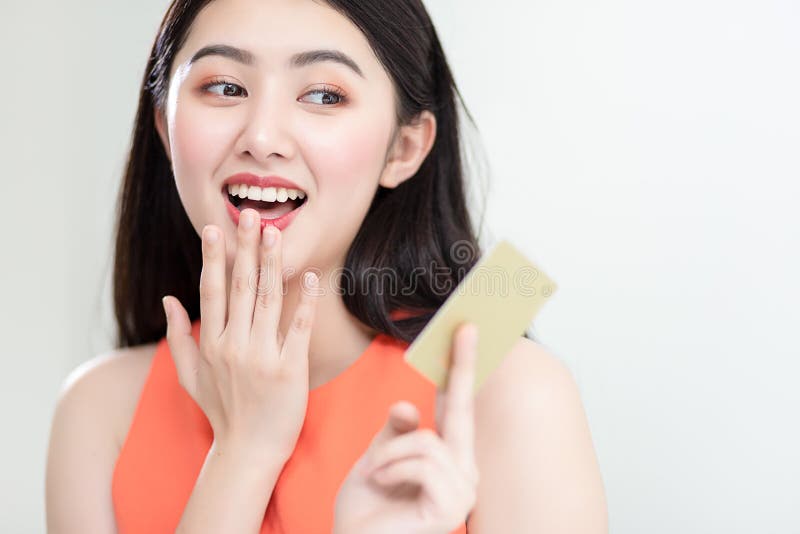 Foto che mostra una ragazza asiatica intelligente con una carta di credito piena di felicità e gioia immagine stock Foto che mostra una ragazza asiatica intelligente con una carta di credito piena di felicità e gioia immagine stock