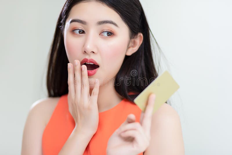 Foto che mostra una ragazza asiatica intelligente con una carta di credito piena di felicità e gioia immagine stock libera da diritti Foto che mostra una ragazza asiatica intelligente con una carta di credito piena di felicità e gioia immagine stock libera da diritti