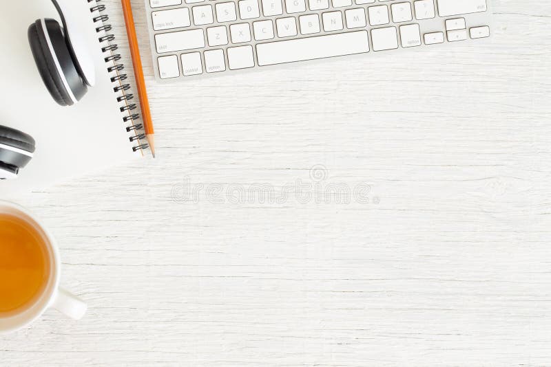 A foto colocada lisa da mesa de escritório com fone de ouvido e teclado, copia o espaço no fundo branco com caderno e lápis, chá foto de stock A foto colocada lisa da mesa de escritório com fone de ouvido e teclado, copia o espaço no fundo branco com caderno e lápis, chá foto de stock