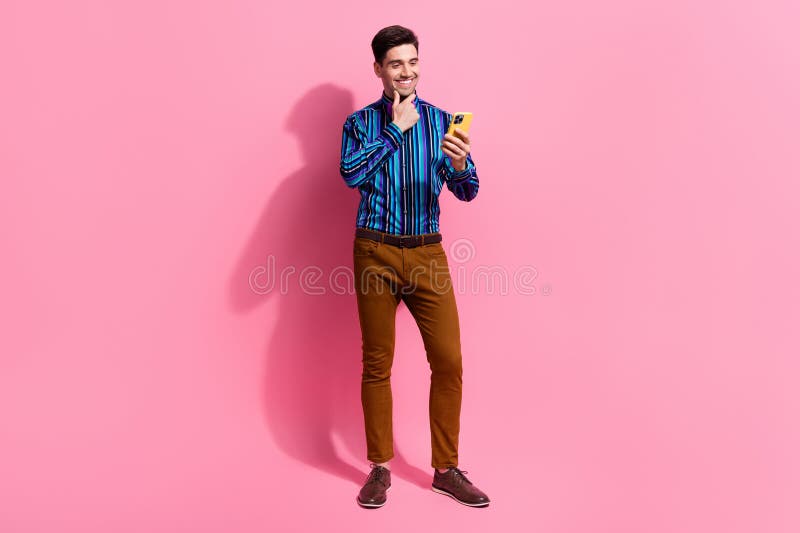 Full length photo of young funny man wear elegant costume touch chin choosing best deal using smartphone isolated on pink color background. Full length photo of young funny man wear elegant costume touch chin choosing best deal using smartphone isolated on pink color background.