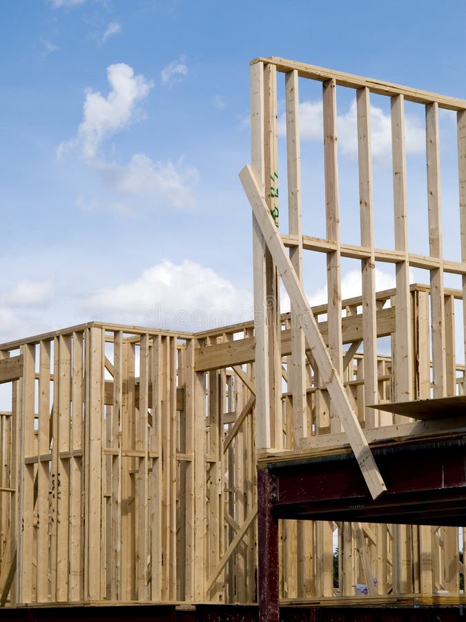 Stock photo of the wood frames of a new urban housing development under construction against a blue sky with white clouds. Stock photo of the wood frames of a new urban housing development under construction against a blue sky with white clouds.