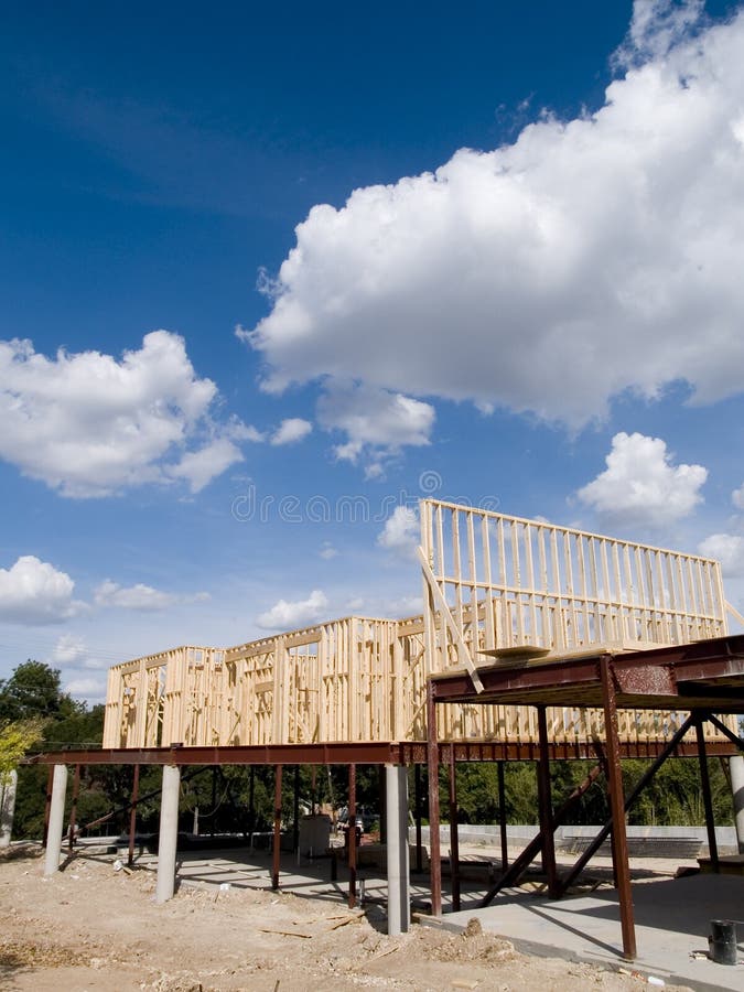 Stock photo of the wood frames of a new urban housing development under construction against a blue sky with white clouds. Stock photo of the wood frames of a new urban housing development under construction against a blue sky with white clouds.