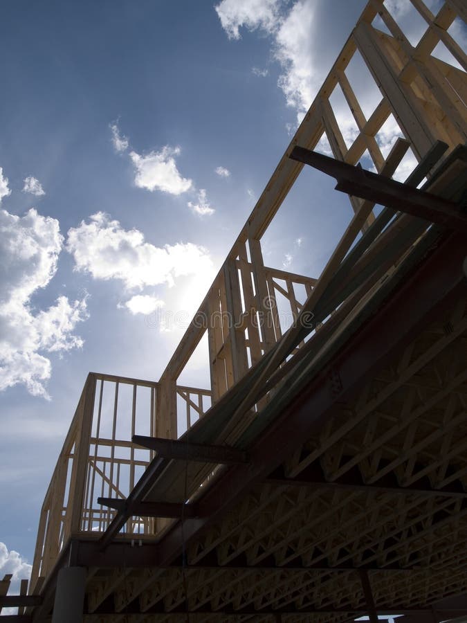 Stock photo of the wood frames of a new urban housing development under construction against a blue sky with white clouds. Stock photo of the wood frames of a new urban housing development under construction against a blue sky with white clouds.