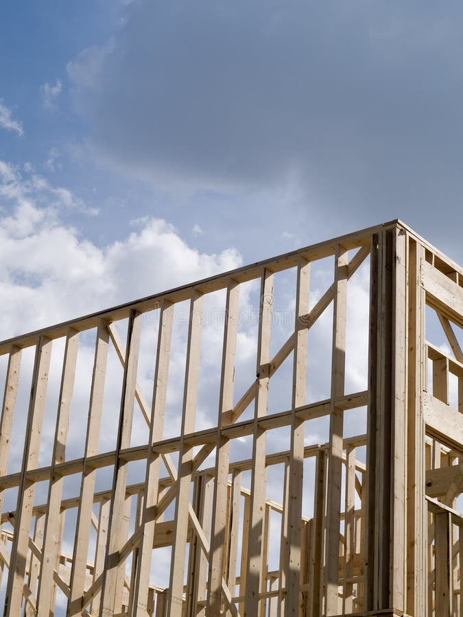 Stock photo of the wood frames of a new urban housing development under construction against a blue sky with white clouds. Stock photo of the wood frames of a new urban housing development under construction against a blue sky with white clouds.