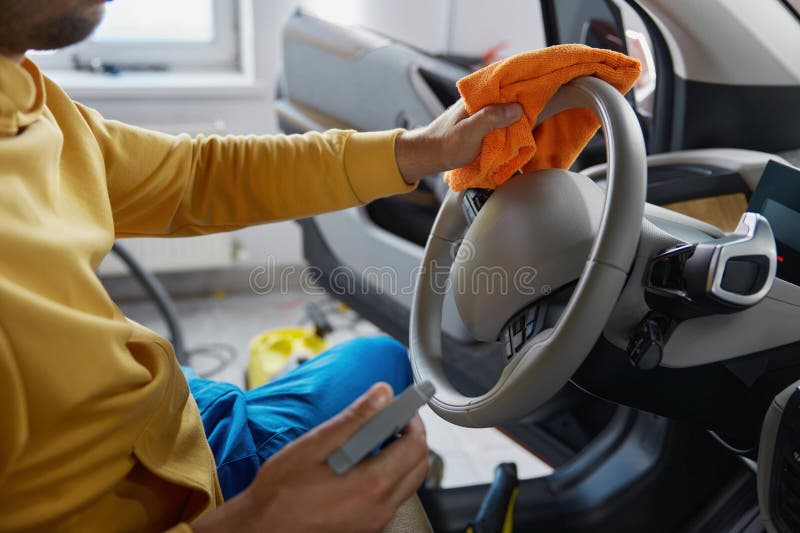 Foto cortada das mãos do homem desinfetando o volante do carro limpando com pano foto de stock