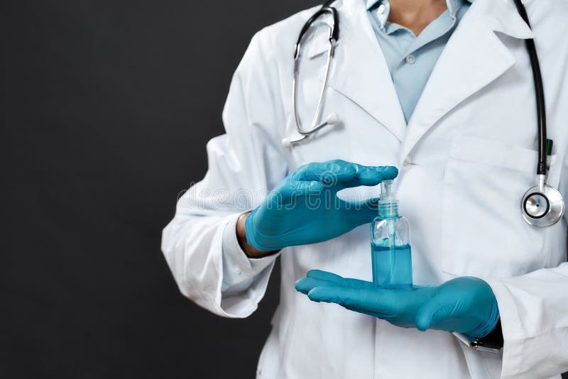 Foto cortada do médico macho em uniforme médico com estetoscópio em volta do pescoço segurando gel antisséptico enquanto em pé imagens de stock
