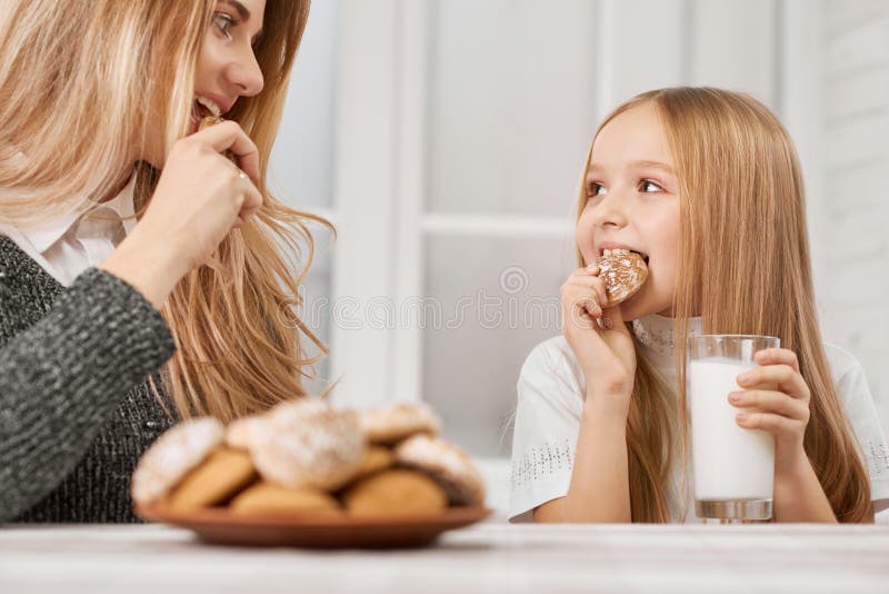 Foto da mãe e da filha que comem cookies e sorriso fotos de stock royalty free Foto da mãe e da filha que comem cookies e sorriso fotos de stock royalty free