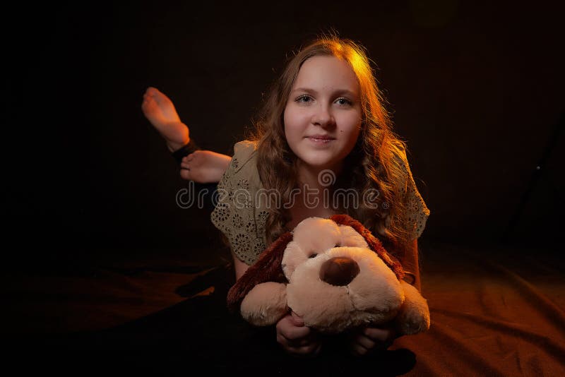 Foto de estudio de una joven adolescente con su juguete de perro suave en las manos. modelo posando sobre fondo negro imágenes de archivo libres de regalías