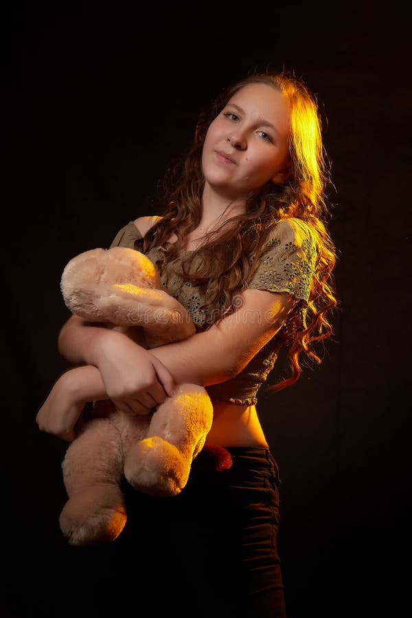 Foto de estudio de una joven adolescente con su juguete de perro suave en las manos. modelo posando sobre fondo negro imagen de archivo