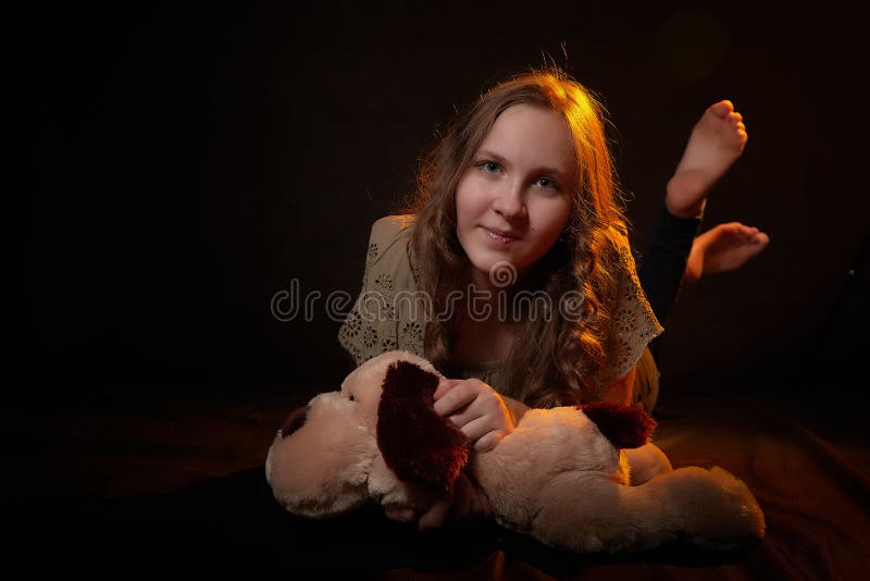 Foto de estudio de una joven adolescente con su juguete de perro suave en las manos. modelo posando sobre fondo negro fotografía de archivo