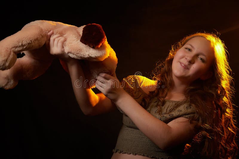 Foto de estudio de una joven adolescente con su juguete de perro suave en las manos. modelo posando sobre fondo negro imagen de archivo