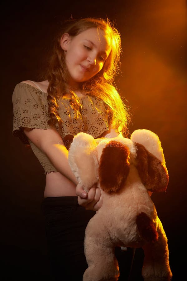 Foto de estudio de una joven adolescente con su juguete de perro suave en las manos. modelo posando sobre fondo negro fotos de archivo libres de regalías