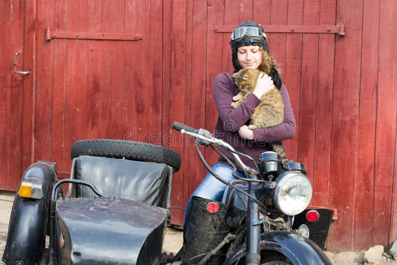 Photo of girl on vintage motorbike in pilot cap with cat. Photo of girl on vintage motorbike in pilot cap with cat