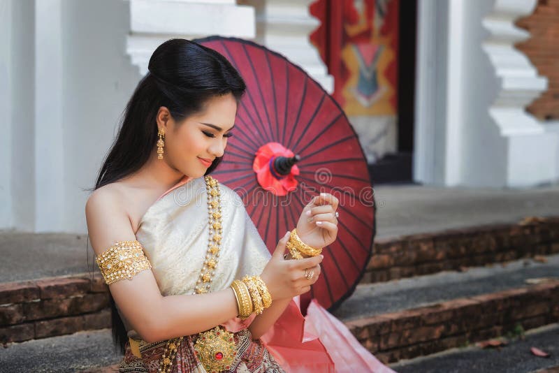 Foto de uma linda mulher tailandesa usando roupas tradicionais tailandesas. ela está usando uma pulseira