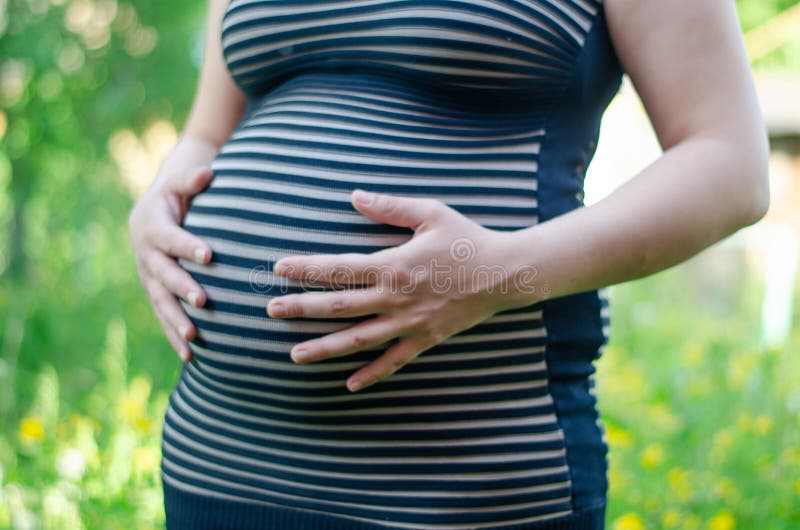 Foto De Una Mujer Embarazada Con Un Vestido a Rayas Con Las Manos En El  Estómago. Cierre Del Vientre Foto de archivo - Imagen de esperar, fondo:  188711604