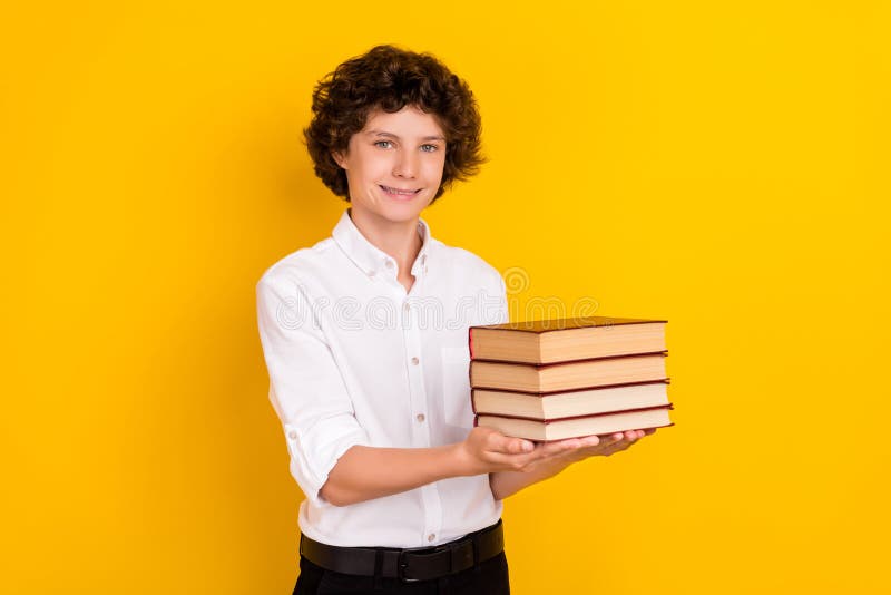 Photo of funny sweet school boy wear white shirt smiling holding book stack isolated yellow color background. Photo of funny sweet school boy wear white shirt smiling holding book stack isolated yellow color background.