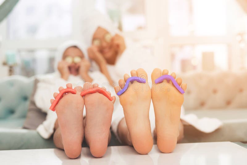 Foto del primer de la hija y de la madre con la esponja para la pedicura en los fingeres Leyeron las revistas en las albornoces b imagenes de archivo Foto del primer de la hija y de la madre con la esponja para la pedicura en los fingeres Leyeron las revistas en las albornoces b imagenes de archivo