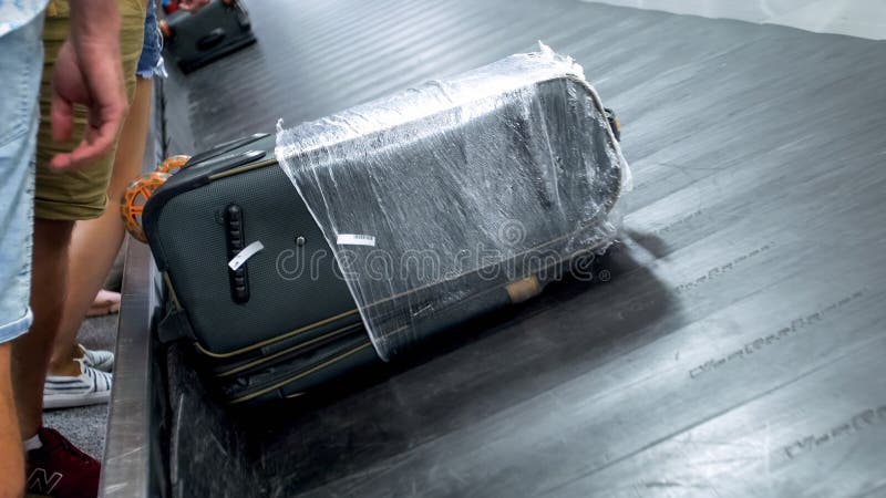 Foto del primo piano delle borse e delle valigie sul nastro trasportatore commovente alla zona di reclamo dei bagagli al terminal immagine stock libera da diritti Foto del primo piano delle borse e delle valigie sul nastro trasportatore commovente alla zona di reclamo dei bagagli al terminal immagine stock libera da diritti