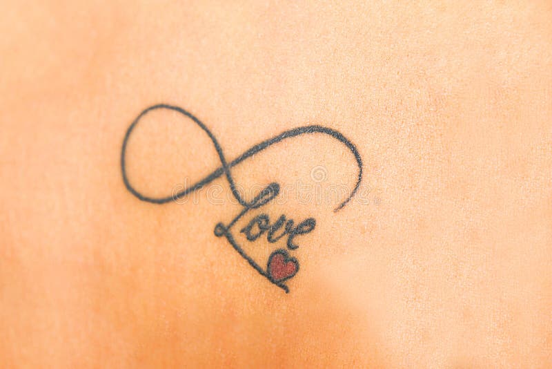 Foto del tatuaggio astratto su pelle che dice l'amore con rosso smal lui fotografia stock Foto del tatuaggio astratto su pelle che dice l'amore con rosso smal lui fotografia stock