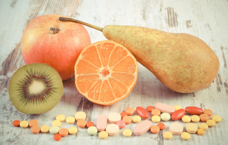 Foto del vintage, frutas frescas y píldoras médicas coloridas, opción entre la nutrición sana y los suplementos médicos fotografía de archivo Foto del vintage, frutas frescas y píldoras médicas coloridas, opción entre la nutrición sana y los suplementos médicos fotografía de archivo