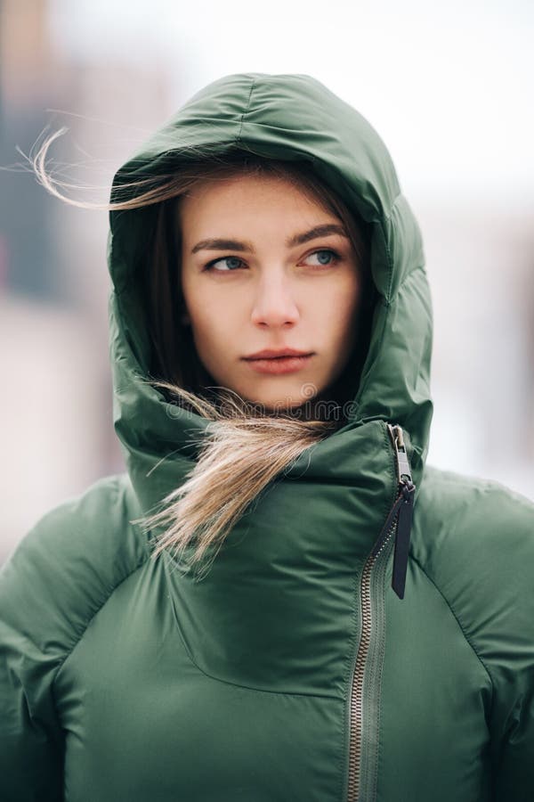 Foto della bionda con capelli lunghi in rivestimento verde su fondo vago fotografia stock Foto della bionda con capelli lunghi in rivestimento verde su fondo vago fotografia stock