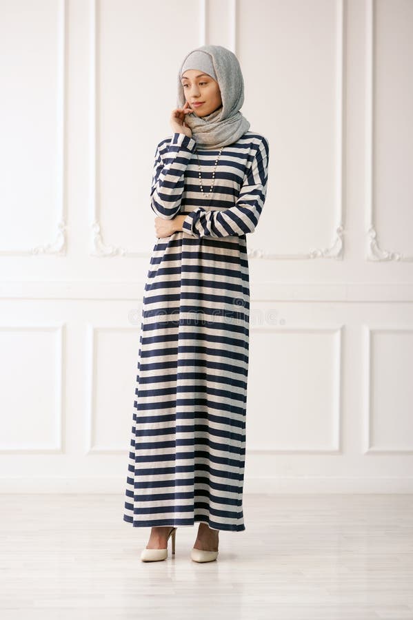Foto dello studio di un tipo orientale della bella giovane donna integrale, su un fondo leggero, vestito nello stile musulmano fotografia stock libera da diritti Foto dello studio di un tipo orientale della bella giovane donna integrale, su un fondo leggero, vestito nello stile musulmano fotografia stock libera da diritti