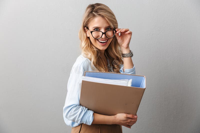 Foto der ansehnlichen blond Sekretärin mit Brillen, die beim Arbeiten im Büro lächelnd und den Aktenordner in der Hand halten stockbild Foto der ansehnlichen blond Sekretärin mit Brillen, die beim Arbeiten im Büro lächelnd und den Aktenordner in der Hand halten stockbild