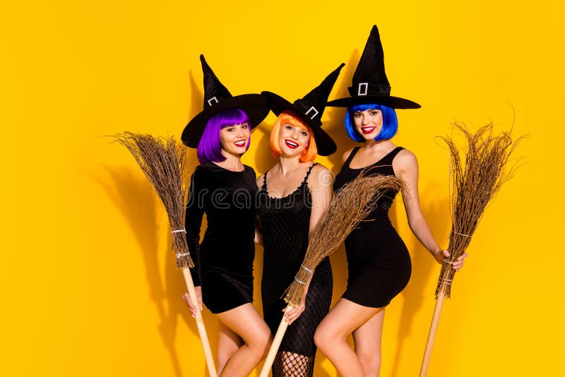 Photo of three in orange blue violet color dyed hairstyle magicians, sorcerers conjurers enchants ready for making brew in cauldron holding brooms isolated vivid color background. Photo of three in orange blue violet color dyed hairstyle magicians, sorcerers conjurers enchants ready for making brew in cauldron holding brooms isolated vivid color background