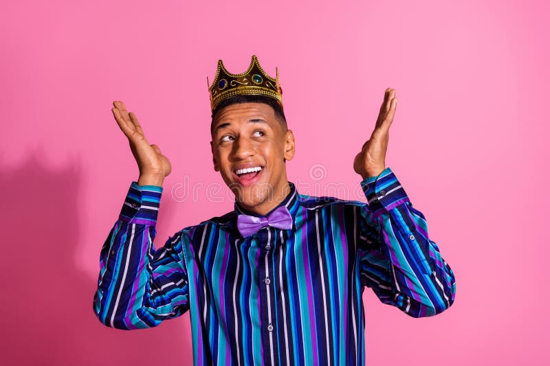 Foto di un allegro ragazzo vestito a strisce con una camicia dorata tiara che sembra vuoto con uno sfondo di colore rosa isolato fotografia stock libera da diritti