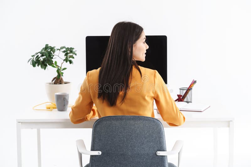 Foto di un'attraente imprenditrice brunette che lavora sul grande computer in un ufficio brillante fotografia stock libera da diritti Foto di un'attraente imprenditrice brunette che lavora sul grande computer in un ufficio brillante fotografia stock libera da diritti