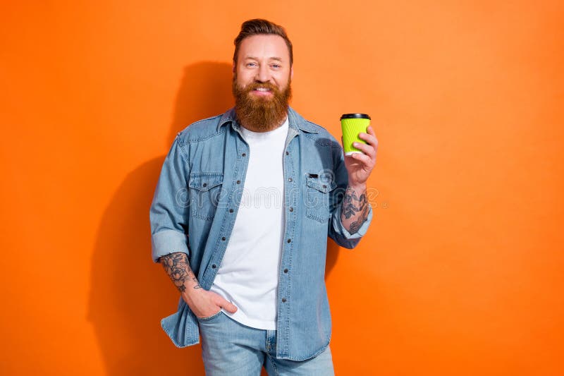Foto di un giovane hipster soddisfatto e felice, tatuato per mano con una tazza di plastica e un cappuccino fresco con energia da immagine stock libera da diritti