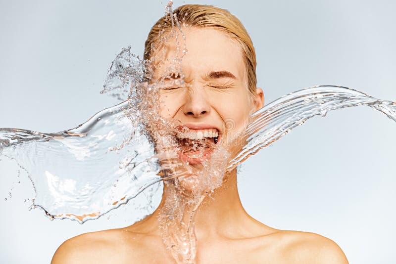 Photo of  screaming woman with drops of water around her face. Young woman with clean skin and splash of water.  Spa treatment. Girl washing her body with water. Water and body. Skin and body care. Photo of  screaming woman with drops of water around her face. Young woman with clean skin and splash of water.  Spa treatment. Girl washing her body with water. Water and body. Skin and body care