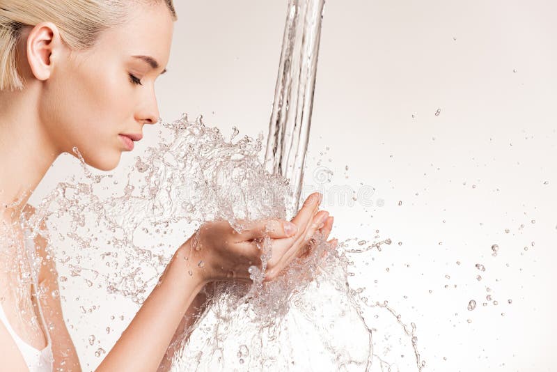 Photo of  young woman with clean skin and splash of water. Blonde woman with drops of water near her face. Spa treatment. Girl washing hands with water. Water and body. Water falling on human hands. Photo of  young woman with clean skin and splash of water. Blonde woman with drops of water near her face. Spa treatment. Girl washing hands with water. Water and body. Water falling on human hands