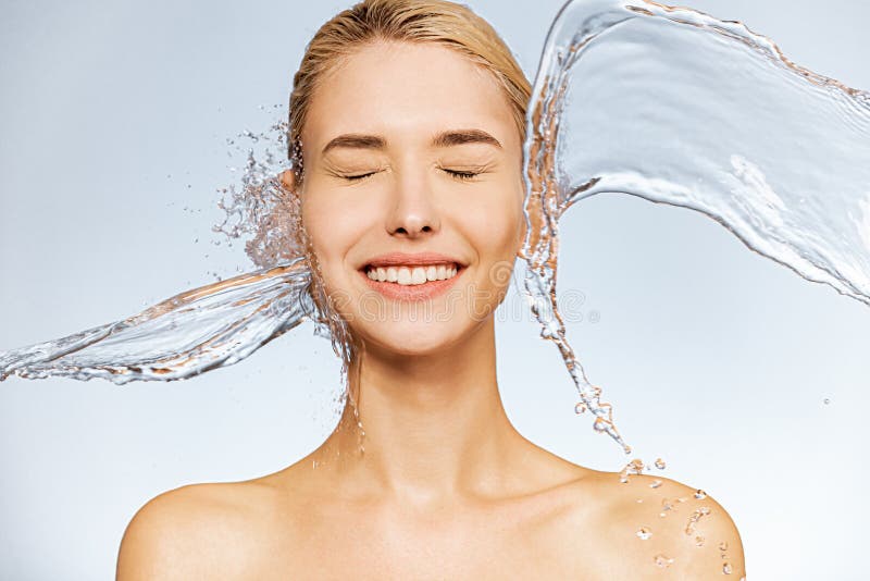 Photo of  young  woman with clean skin and splash of water. Portrait of smiling woman with drops of water around her face. Spa treatment. Girl washing her body with water. Water and body. Photo of  young  woman with clean skin and splash of water. Portrait of smiling woman with drops of water around her face. Spa treatment. Girl washing her body with water. Water and body