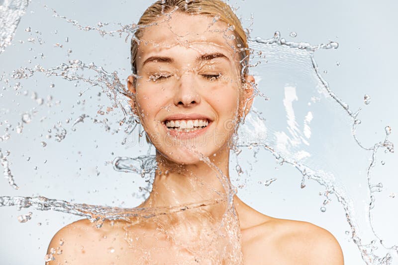 Photo of  young  woman with clean skin and splash of water. Portrait of smiling woman with drops of water around her face. Spa treatment. Happy girl washing her body with water. Water and body. Photo of  young  woman with clean skin and splash of water. Portrait of smiling woman with drops of water around her face. Spa treatment. Happy girl washing her body with water. Water and body