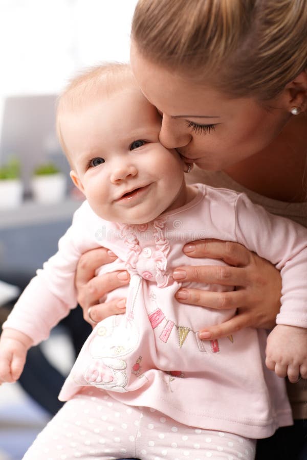 Foto do close up da mãe que beija o bebê feliz foto de stock royalty free