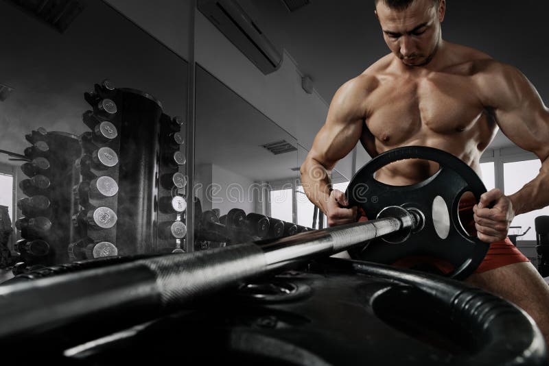 A foto do close up do indivíduo considerável do halterofilista prepara-se para fazer exercícios com barbell em um gym, mantém a p foto de stock royalty free