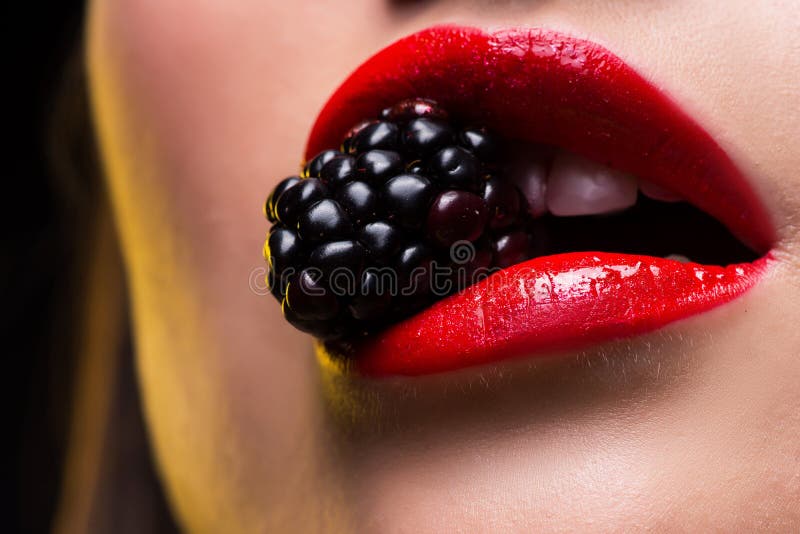 Foto do close up dos bordos fêmeas vermelhos com a amora-preta nos dentes fotos de stock Foto do close up dos bordos fêmeas vermelhos com a amora-preta nos dentes fotos de stock