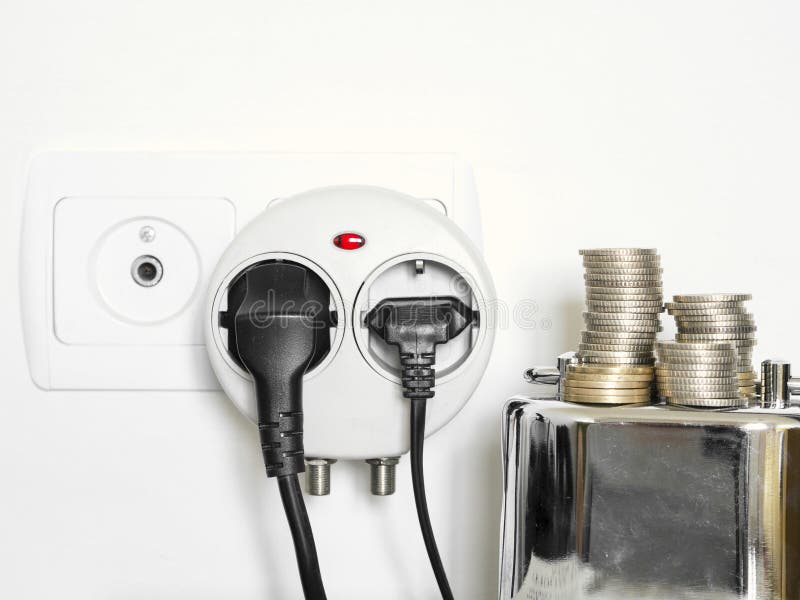 A foto do conceito com mealheiro e as moedas que mostram a tomada e o consumo de eletricidade obstruíram dentro a tomada de pared imagens de stock A foto do conceito com mealheiro e as moedas que mostram a tomada e o consumo de eletricidade obstruíram dentro a tomada de pared imagens de stock