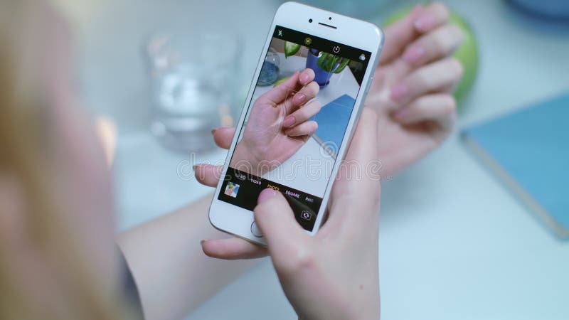 Foto do tratamento de mãos da mulher no telefone celular A foto entrega o verniz para as unhas