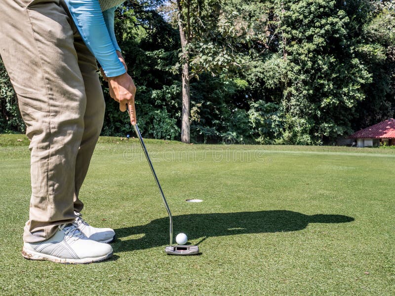 Foto dos golfistas estão colocando golfe no buraco com um punho na grama verde imagem de stock Foto dos golfistas estão colocando golfe no buraco com um punho na grama verde imagem de stock